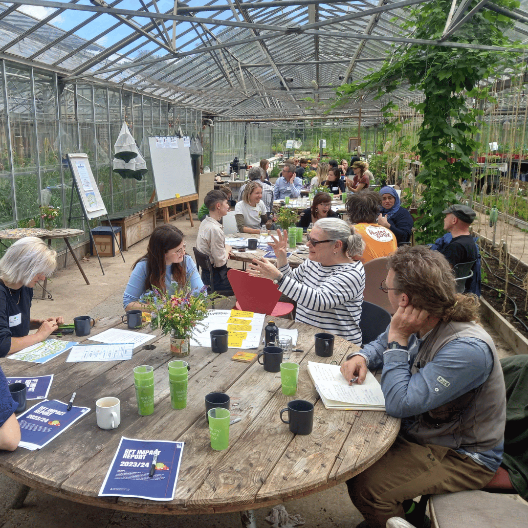 A group of better food traders gather around tables chatting at the annunal gathering 2025