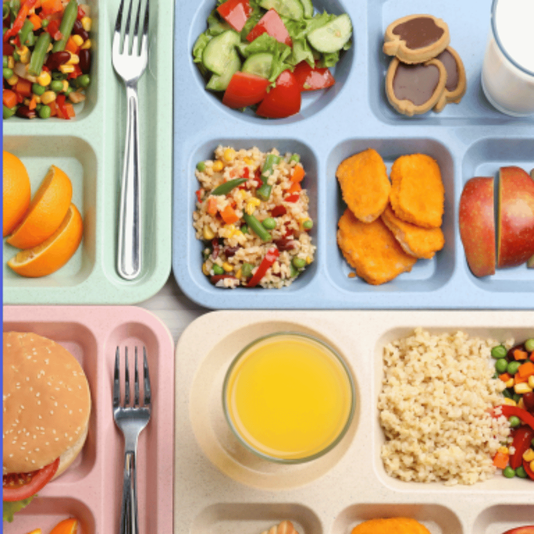 A table full of trays with fresh food on it, like in a school canteen.
